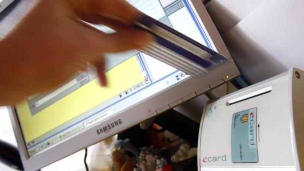 Eine Hand führt eine elektronische Gesundheitskarte in ein Lesegerät ein.