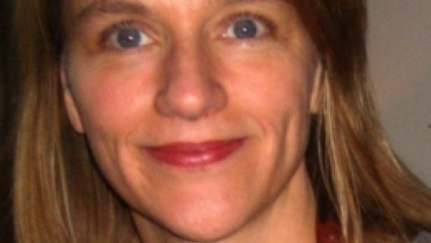 Eine Frau mit blonden Haaren und einer bunten Halskette blickt in die Kamera.