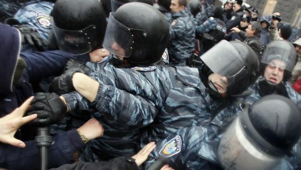 Polizisten in Kampfmontur drängen sich in einer Menschenmenge.