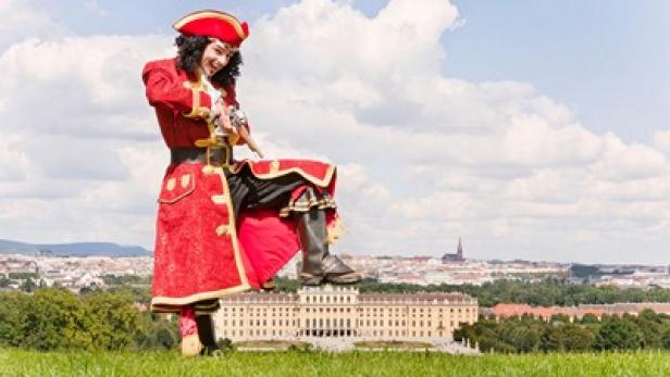 Eine Person im Piratenkostüm steht mit einem Fuß auf Schloss Schönbrunn in Wien.