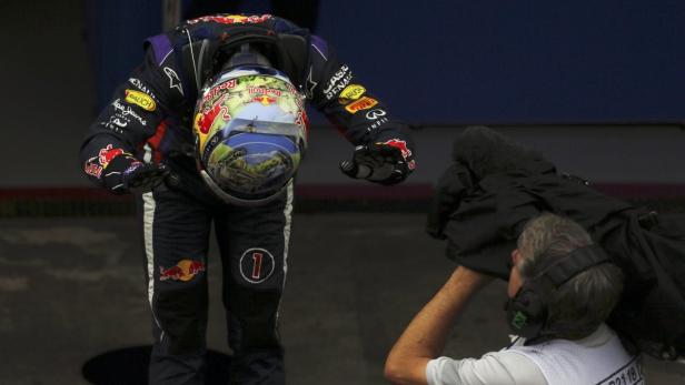 Ein Formel-1-Fahrer mit gesenktem Kopf hält seinen Helm in der Hand.