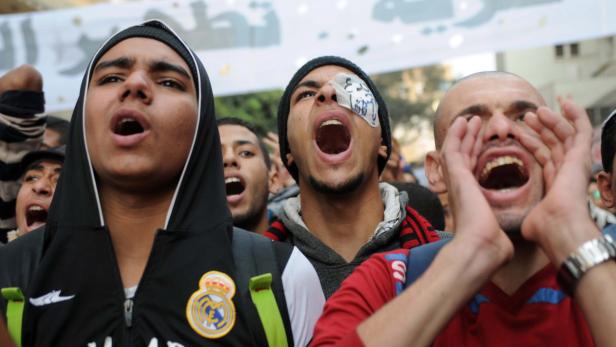 Eine Gruppe junger Männer schreit bei einer Demonstration.