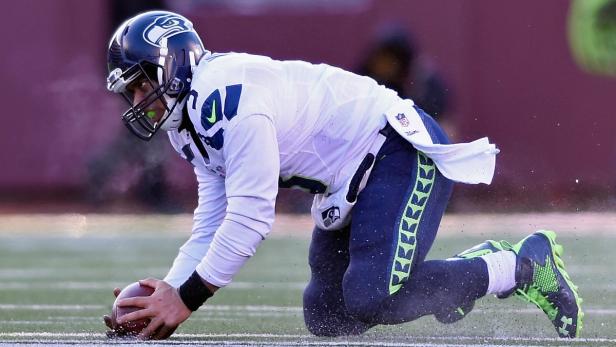 Ein Footballspieler der Seattle Seahawks kniet und hält einen Football auf dem Spielfeld.