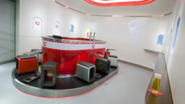 Eine Bar mit Flugzeugfenstern und roten Akzenten, die an das Innere eines Flugzeugs erinnert.
