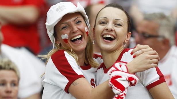 Zwei lachende polnische Fußballfans umarmen sich.