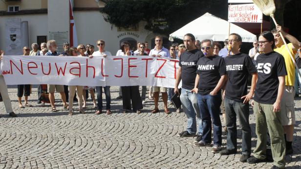Eine Gruppe von Menschen demonstriert mit einem Banner, auf dem „Neuwahl JETZT“ steht.
