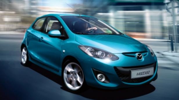 Ein türkisfarbener Mazda 2 fährt auf einer Straße.