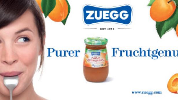 Eine Frau hält einen Löffel im Mund, daneben ein Glas Aprikosenmus von Zuegg.