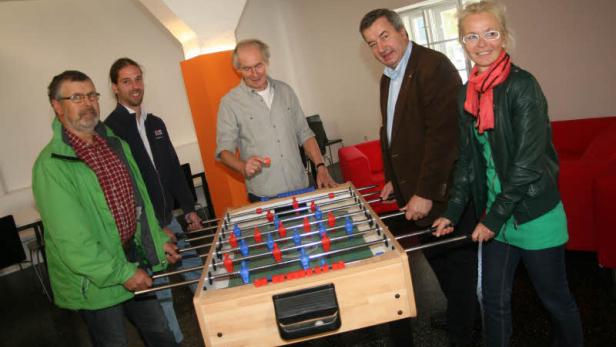 Eine Gruppe von fünf Personen spielt Tischfußball.
