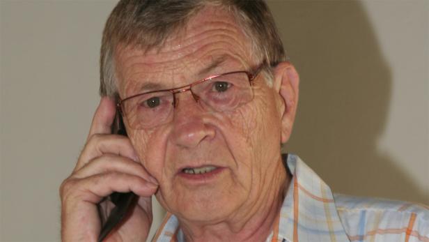 Ein älterer Mann mit Brille telefoniert.