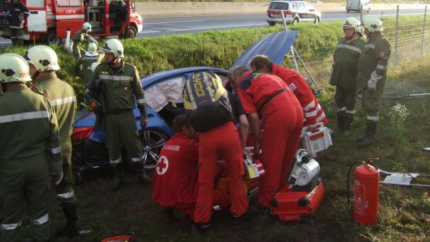 Rettungskräfte arbeiten an einem Unfallwagen auf der Autobahn.