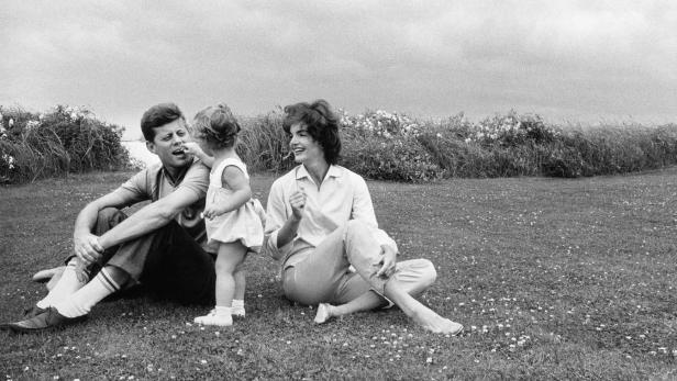 John F. Kennedy, Jackie Kennedy und ihre Tochter sitzen auf einer Wiese.