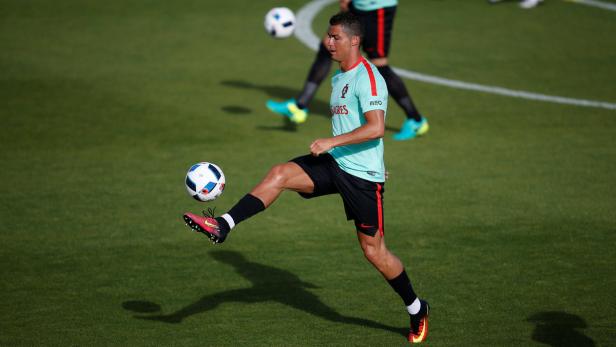 Cristiano Ronaldo jongliert mit einem Fußball auf einem grünen Rasen.