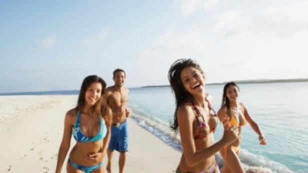 Eine Gruppe junger Leute läuft am Strand entlang.