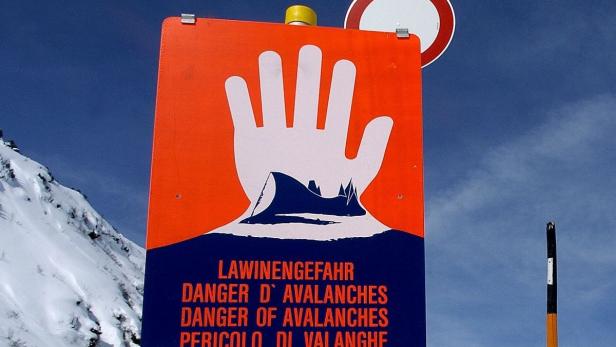 Ein Schild warnt vor Lawinengefahr in den Bergen.