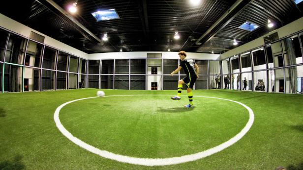Ein Fußballspieler schießt einen Ball auf einem Indoor-Fußballfeld.