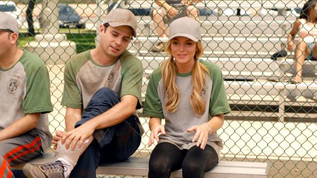Lindsay Lohan sitzt mit anderen Schauspielern auf einer Bank am Set von „Herbie Fully Loaded“.