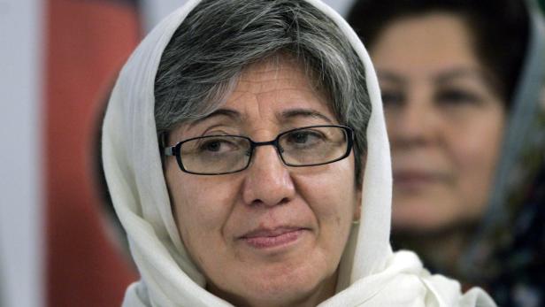 Eine Frau mit Brille und weißem Kopftuch blickt in die Ferne.