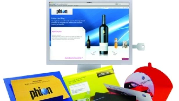 Ein Computerbildschirm zeigt die Webseite von „Phion“, umgeben von verschiedenen Werbematerialien.