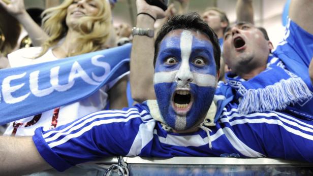 Ein griechischer Fan mit blau-weiß bemalten Gesicht feuert sein Team an.
