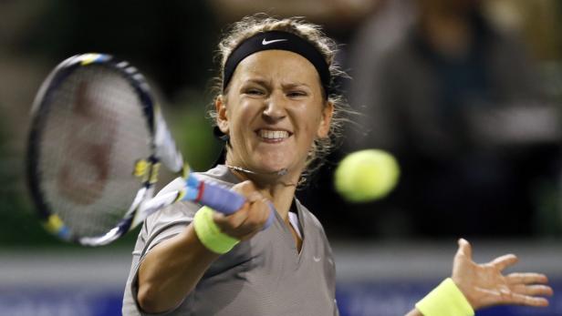 Eine Tennisspielerin schlägt mit einem Tennisschläger einen Ball.