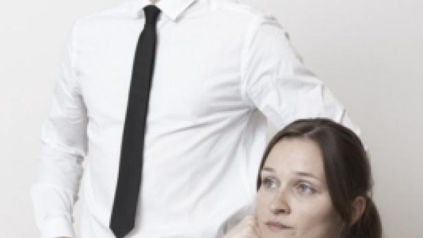 Ein Mann im Hemd und eine Frau sitzen an einem Tisch und schauen in verschiedene Richtungen.