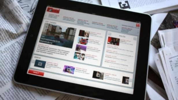 Ein Tablet-Computer liegt auf einem Stapel Zeitungen.