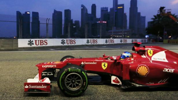 Ein roter Ferrari-Rennwagen auf einer Rennstrecke mit der Skyline von Singapur im Hintergrund.
