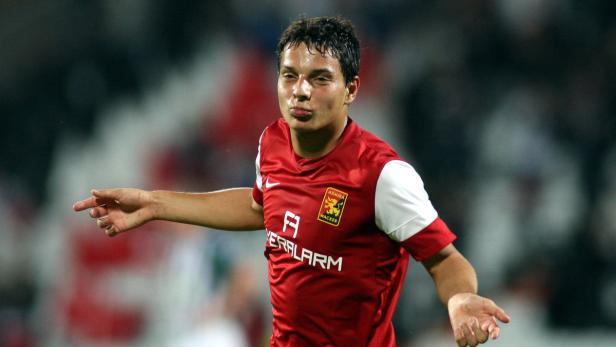 Ein Fußballspieler im roten Trikot mit dem Logo von Admira Wacker Mödling gestikuliert.