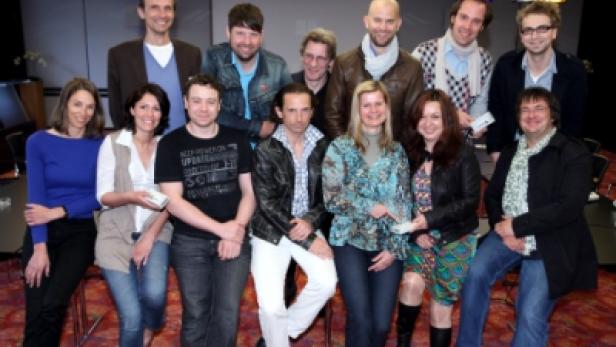 Eine Gruppe von elf Personen posiert für ein Gruppenfoto in einem Innenraum.