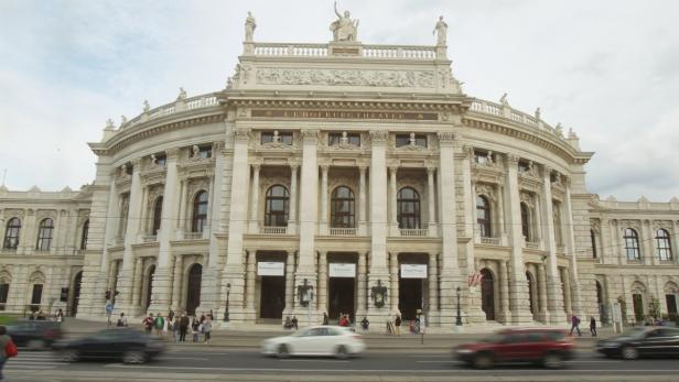 Das Burgtheater in Wien mit Passanten und Autos davor.