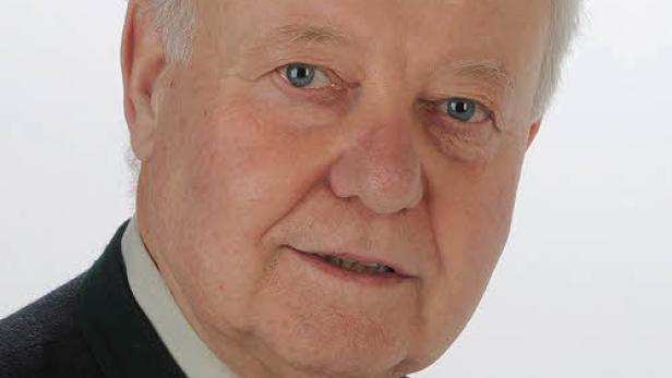 Porträt eines älteren Mannes mit hellen Haaren und einem dunklen Anzug.