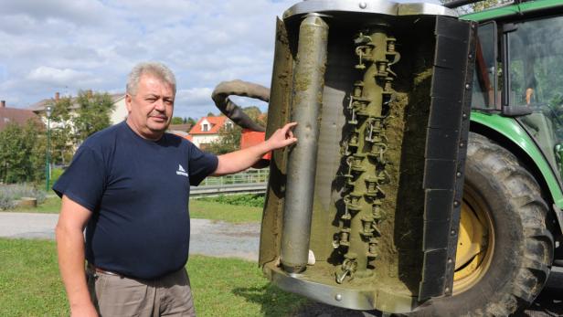 Ein Mann steht neben einem Traktor mit einem angebauten Schlegelmulcher.