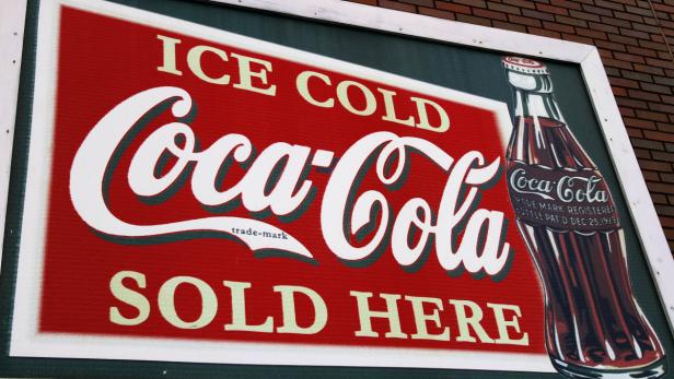 Ein Schild wirbt mit dem Slogan „Ice Cold Coca-Cola Sold Here“ und einer Abbildung der klassischen Flasche.