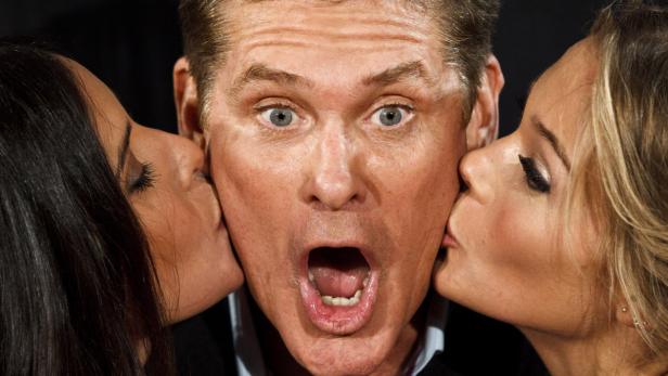 David Hasselhoff wird von zwei Frauen auf die Wange geküsst.