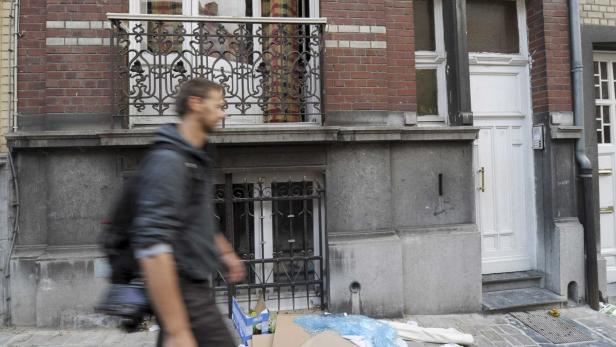 Ein Mann geht an einem Backsteingebäude mit einem kleinen Balkon vorbei.