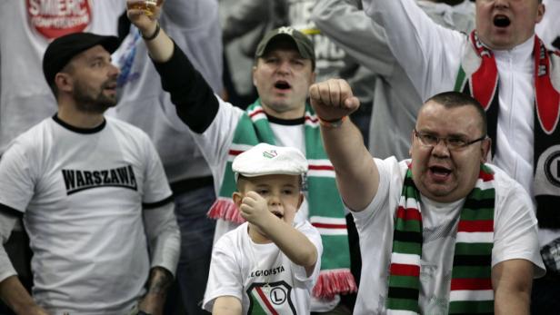 Eine Gruppe von Fußballfans, darunter ein Kind, feuern ihre Mannschaft an.