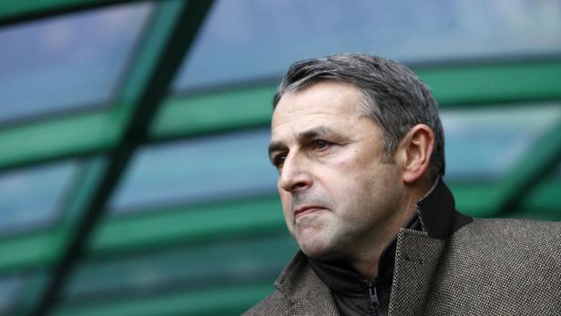 Ein Mann mit grauem Haar und einem Tweed-Jackett blickt nachdenklich zur Seite.