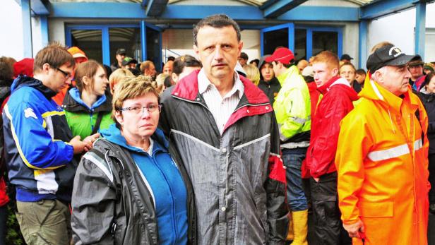 Eine Menschenmenge steht vor einem Gebäude mit blauen Türen.