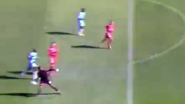 Ein Fußballtorwart springt, um einen Ball während eines Spiels zu fangen.