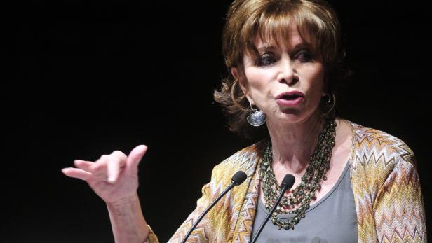 Isabel Allende spricht bei einer Veranstaltung vor zwei Mikrofonen.