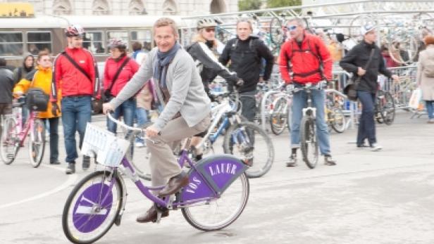 Ein Mann fährt auf einem lila Leihfahrrad durch eine Menschenmenge.