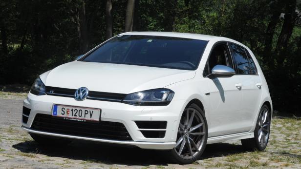 Ein weißer VW Golf R steht auf einem gepflasterten Weg.