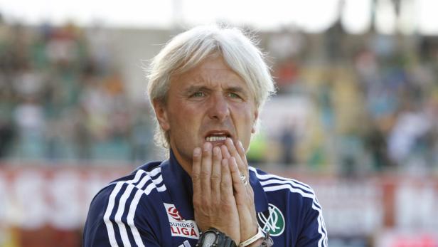 Ein Mann mit grauen Haaren in Sportkleidung hält die Hände vor das Gesicht.