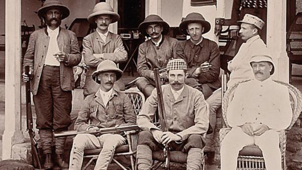 Eine Gruppe von Männern in Safari-Kleidung posiert mit Gewehren für ein Foto.