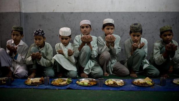 Eine Gruppe muslimischer Jungen betet vor dem Essen.