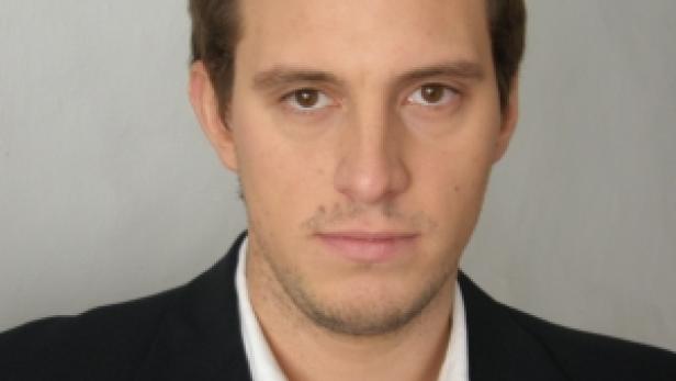 Ein Mann mit braunen Haaren und einem dunklen Anzug blickt in die Kamera.