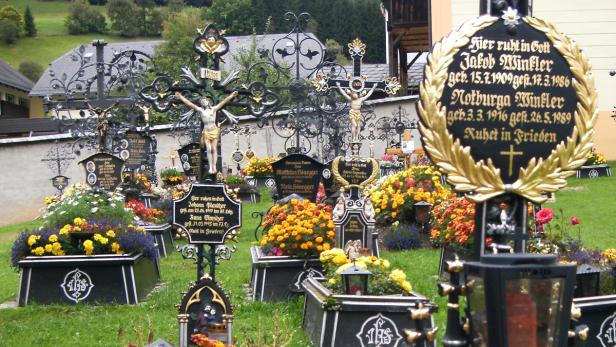 Ein Friedhof mit kunstvollen Grabsteinen und bunten Blumen geschmückt.