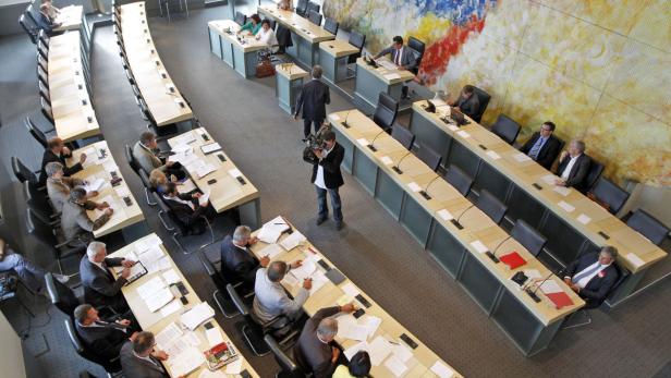 Eine Aufsicht auf einen Sitzungssaal mit mehreren Personen an Tischen.