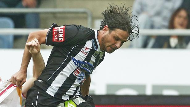 Ein Fußballspieler im schwarz-weiß gestreiften Trikot während eines Spiels.